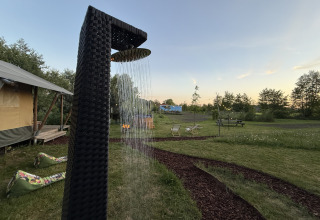 Douche extérieure près de la tente safari Koakelbonts Lovenest à Gelderland, avec pelouse et espaces détente.
