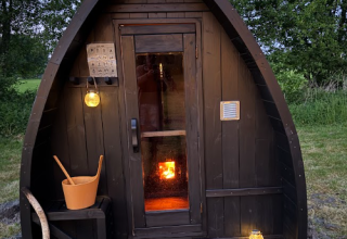 Udendørs sauna-lignende hytte ved Koakelbonts Lovenest - Safaritent Gelderland i skovområde ved skumring.