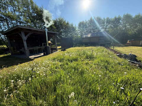 Glamping Koakelbonts Lovenest in Gelderland met safaritent, terras en omringd door groene natuur en zon.
