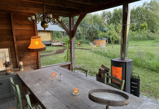 Overdekte eettafel met houtkachel en safaritent op de achtergrond bij Koakelbonts Lovenest, Gelderland.