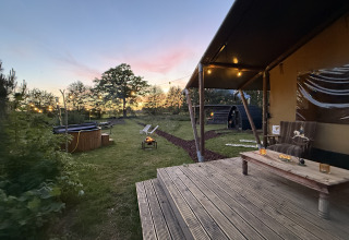 Soirée au Koakelbonts Lovenest - Safaritent Gelderland avec terrasse, feu de camp et guirlandes lumineuses.