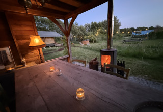 Gemütliches Safarizelt bei Koakelbonts Lovenest in Gelderland, Holland, mit ländlichem Tisch und Lagerfeuer.