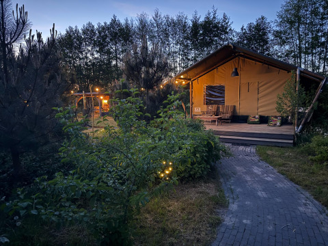 Hébergement glamping Koakelbonts Lovenest en Gueldre, Pays-Bas, avec tente safari au crépuscule.