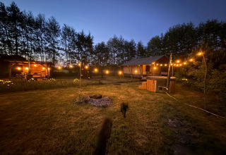 Alojamiento glamping Koakelbonts Lovenest - Safaritent Gelderland iluminado con guirnaldas en el atardecer.