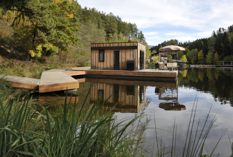 Flydende hjem ved søen i Nature Resort Natterer See, omgivet af natur og træer, perfekt til glamping.