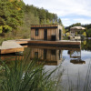 Floating glamping accommodation at Nature Resort Natterer See, set on a tranquil lake surrounded by trees.