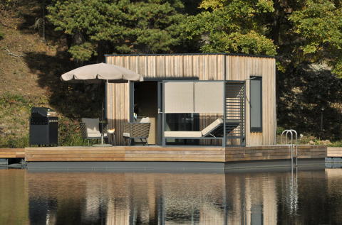 Casa galleggiante al Nature Resort Natterer See in Tirolo, con terrazza in legno moderna e vista sul lago.