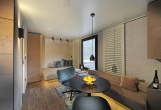 Moderne glampingbolig i Nature Resort Natterer See - Floating Homes Tirol, træinteriør og komfortable møbler.