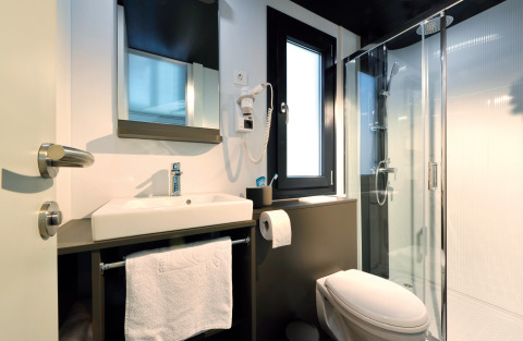 Moderne badeværelse med bruser og toilet i floating home på Nature Resort Natterer See, Tirol, Østrig.