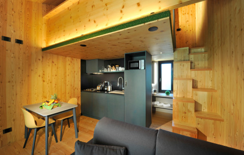Modern wooden Tiny House Tirol with kitchenette, dining table, and stairs, glamping at Nature Resort Natterer See.