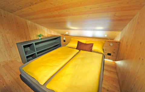 Alojamiento Tiny House Tirol en Nature Resort Natterer See con techos inclinados y ropa de cama amarilla.