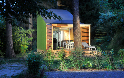 Illuminated glamping accommodation at Nature Resort Natterer See - Tiny House Tirol, surrounded by a lush forest.