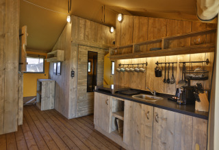 Houten keukeninterieur in de glampingtent 'Frei wie der Wind - Safaritenten aan de Oostzee' met sfeervolle verlichting.