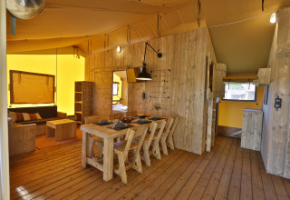 Intérieur d'une tente glamping de luxe avec meubles en bois, table à manger et salon douillet près de la Baltique.