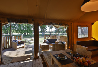 Interior de tienda glamping con mobiliario de madera y terraza en Frei wie der Wind cerca del mar Báltico.