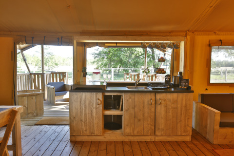 Cozy glamping kitchen in a safari tent at Frei wie der Wind by the Baltic Sea, opening to a wooden terrace.