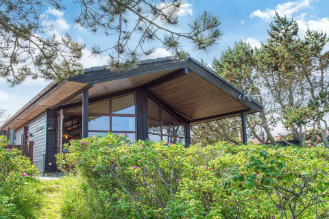 Casa de vacaciones moderna para 4 personas en Glesborg, rodeada de vegetación y árboles bajo el cielo azul.