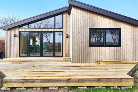 Moderne lodge med træfacade og stor terrasse i Sydals, set fra forsiden, ideel til ferieophold.