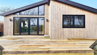 Modernes Ferienhaus mit Holzverkleidung und geräumiger Terrasse in Sydals, ideal für Erholung.