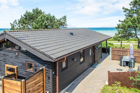 Ferielodge i Glesborg, Danmark, med sort træbeklædning og havudsigt, omgivet af natur og terrasse.