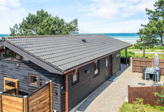Casa vacanze a Glesborg, Danimarca, con esterno in legno nero, terrazza e splendida vista mare.