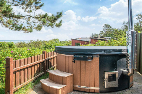 Bain à remous extérieur en bois avec marches, vue sur la mer et verdure à Glesborg, Danemark.