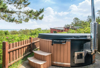 Vasca idromassaggio esterna in legno con gradini, vista mare e verde a Glesborg, Danimarca.