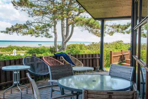 Vista desde la terraza de una casa de vacaciones en Glesborg, Dinamarca, con mobiliario y vista al mar.