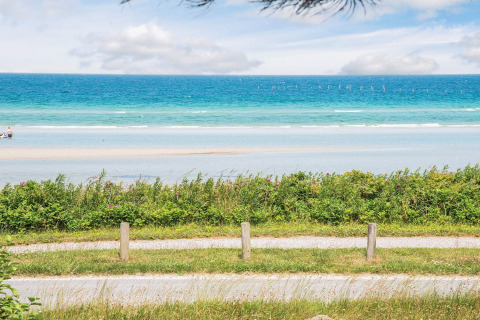 Aussicht auf das Meer von einem Ferienhaus in Glesborg, Dänemark, mit Sandstrand und Pflanzen.