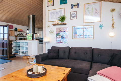 Lyst og hyggeligt opholdsområde i et sommerhus i Glesborg, Danmark, med moderne indretning og kunst på væggen.