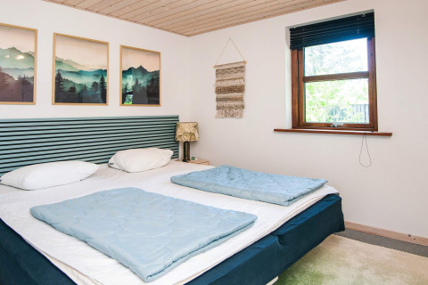 Bedroom with double bed, nature artwork, and window in a 4-person holiday home in Glesborg, Denmark.