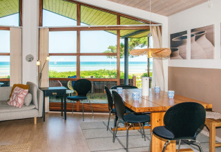 Stue med store vinduer og havudsigt i en feriebolig i Glesborg, Danmark, med moderne indretning.
