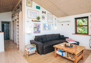 Cozy living room in a Glesborg holiday home, Denmark, featuring a dark sofa, wood table, and wall art.