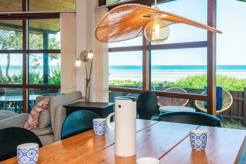 Eetruimte in een vakantiehuis in Glesborg, Denemarken, met grote ramen en uitzicht op zee en strand.
