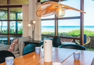 Salle à manger d'une maison de vacances à Glesborg, Danemark, avec de grandes fenêtres sur la plage.