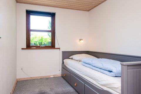 Et lyst, enkelt soveværelse med enkeltseng og vindue, set på feriebolig for 4 personer i Glesborg, Danmark.