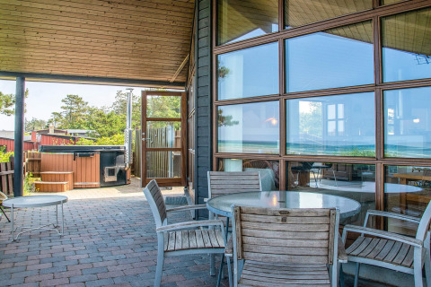 Covered patio with wooden furniture and hot tub at the 4 person holiday home in Glesborg, Denmark.