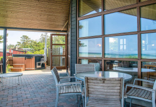 Overdekt terras met houten zitset en jacuzzi aan 4-persoons vakantiewoning in Glesborg, Denemarken.