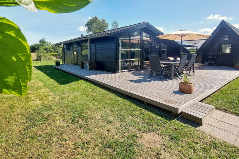 Vue extérieure d'une maison de vacances pour 6 personnes à Hemmet, Danemark, avec terrasse en bois et pelouse verte.