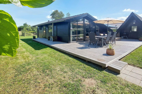 Außenaufnahme eines 6-Personen-Ferienhauses in Hemmet, Dänemark, mit Holzterrasse, Gartenmöbeln und Rasen.