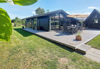 Vista exterior de casa de vacaciones para 6 personas en Hemmet, Dinamarca, con terraza de madera y jardín verde.