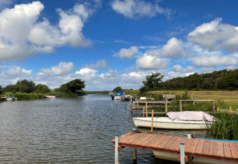 Rivière paisible avec bateaux près du gîte 6 personnes à Hemmet, Danemark, sous ciel bleu.
