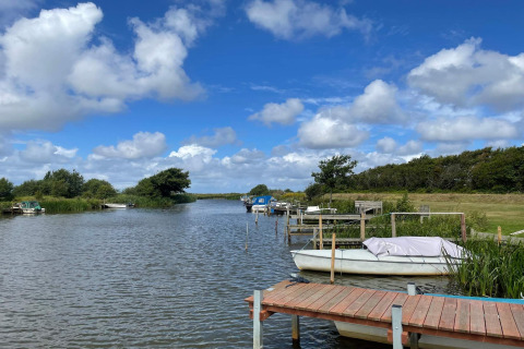 Rustig rivierlandschap met boten bij het 6-persoons vakantiehuis in Hemmet, Denemarken, onder blauwe lucht.