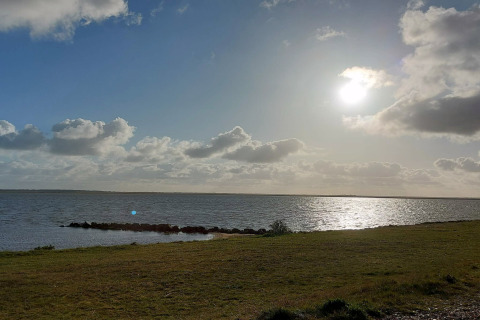 Udsigt over en sø og vindskyer ved solnedgang fra 6 personers feriehus i Hemmet, Danmark.