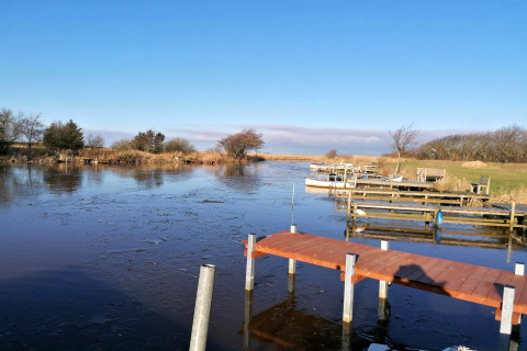 Vue sur un lac gelé avec pontons et barques près d'une maison de vacances pour 6 personnes à Hemmet, Danemark.