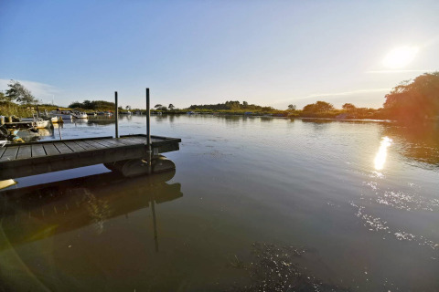 Vue ensoleillée sur un lac calme avec quai et bateaux près d'une maison de vacances à Hemmet, Danemark.