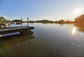 Vue ensoleillée sur un lac calme avec quai et bateaux près d'une maison de vacances à Hemmet, Danemark.