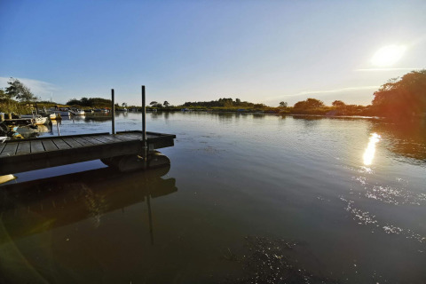 Vue ensoleillée sur un lac calme avec quai et bateaux près d'une maison de vacances à Hemmet, Danemark.