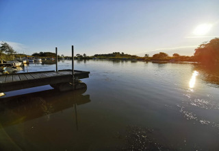 Vista soleggiata su un lago tranquillo con pontile e barche presso casa vacanze per 6 a Hemmet, Danimarca.
