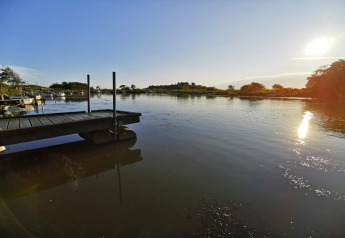 Sonniger Ausblick auf einen ruhigen See mit Steg und Booten am 6-Personen-Ferienhaus in Hemmet, Dänemark.